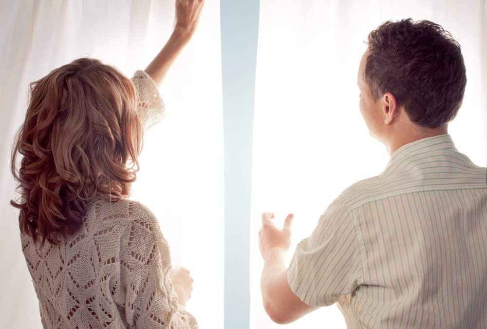 man and woman hanging curtains